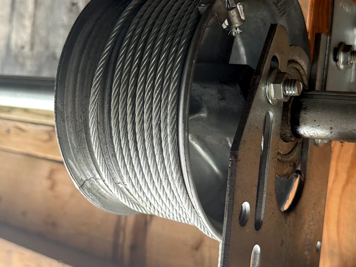 Close view of a garage door cable drum and torsion hardware
