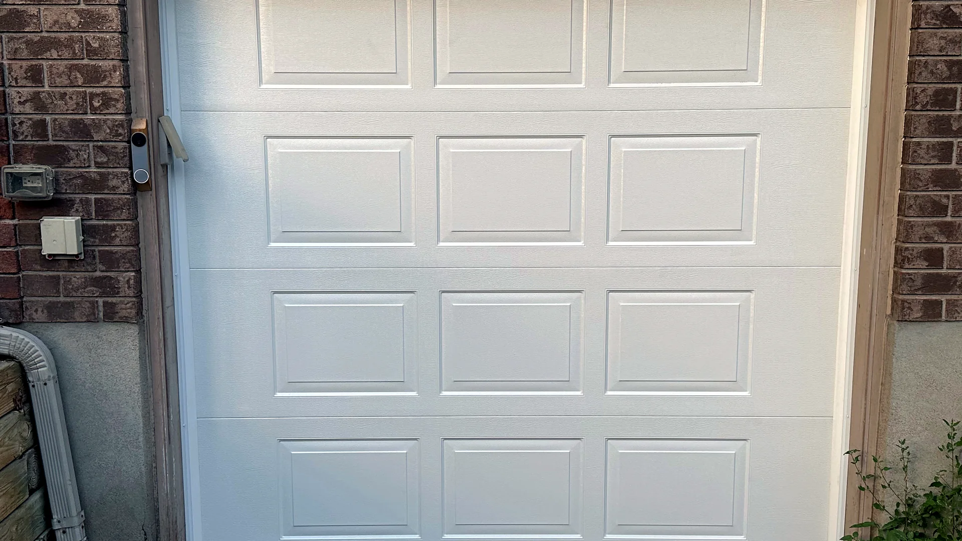 White raised-panel single garage door in a brick opening
