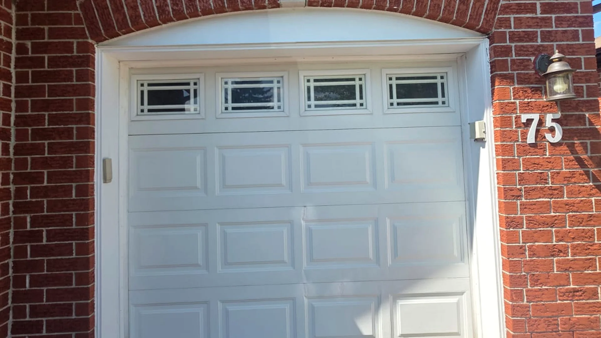 Older white sectional garage door at a Calgary home ready for service assessment
