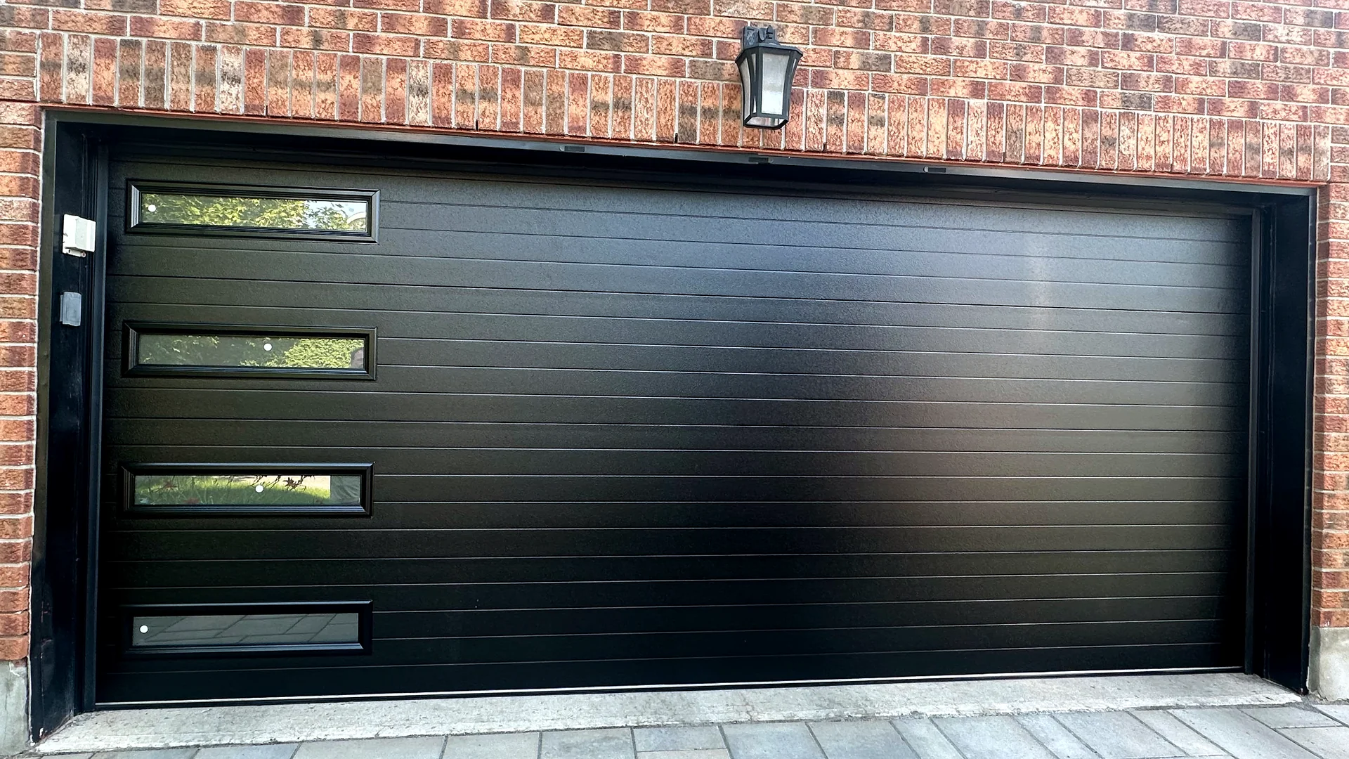 Modern black sectional garage door with offset windows for a Calgary installation page