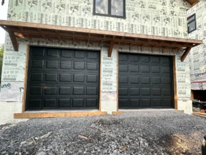 Two black raised-panel garage doors installed during new home construction