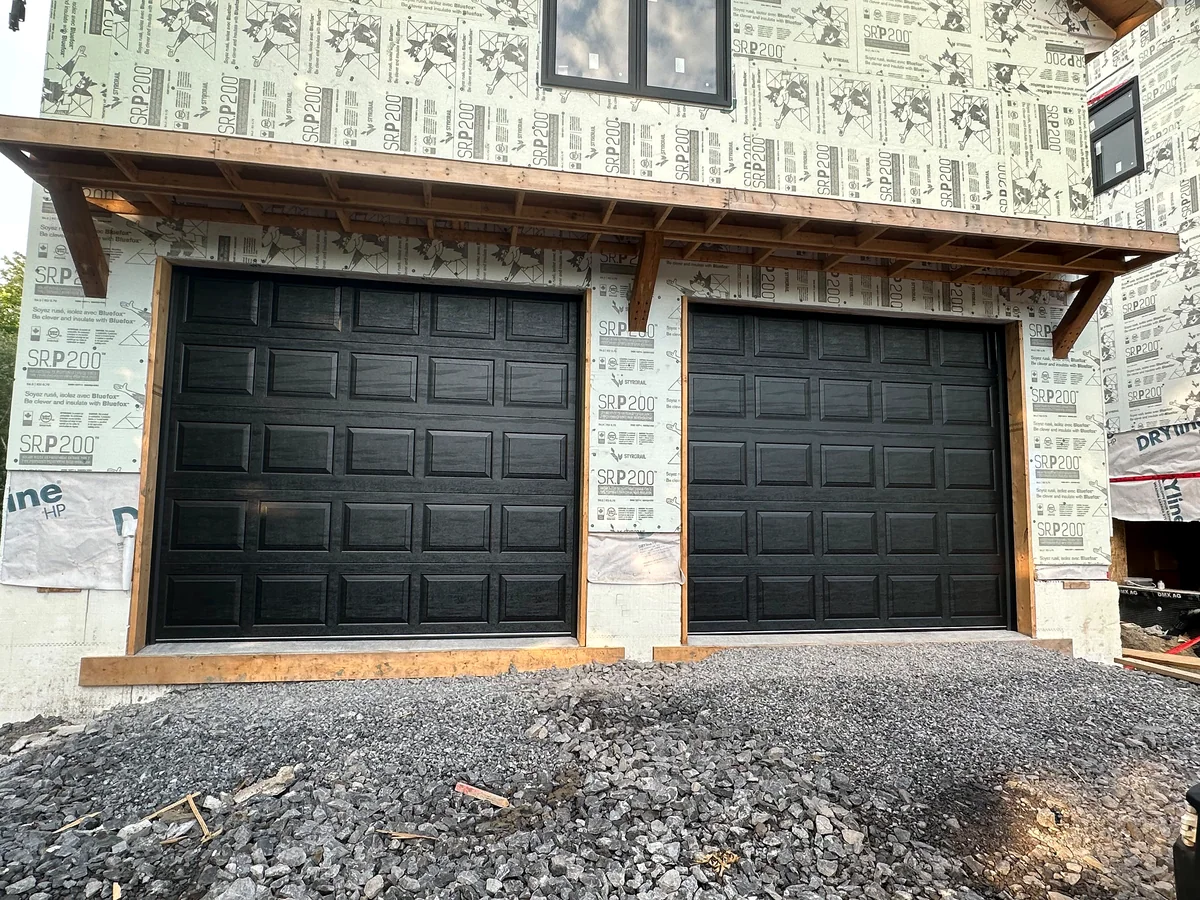 Two black raised-panel garage doors installed during new home construction