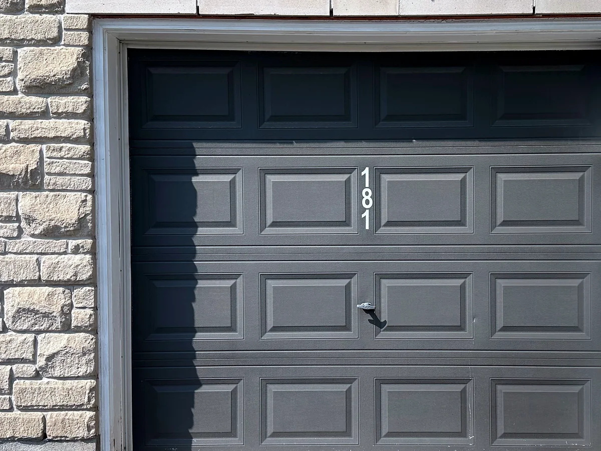 Dark raised-panel single garage door in a stone opening