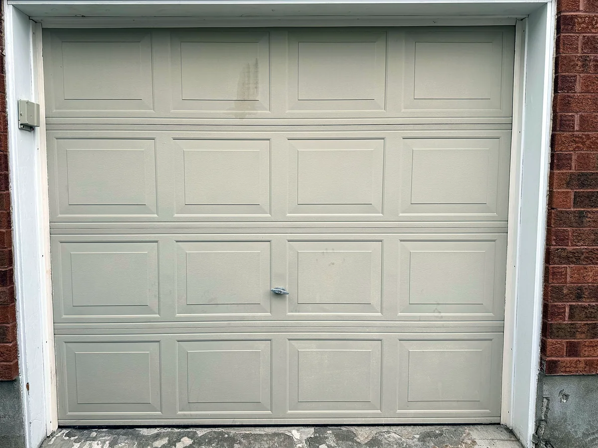 Weathered white raised-panel garage door ready for assessment