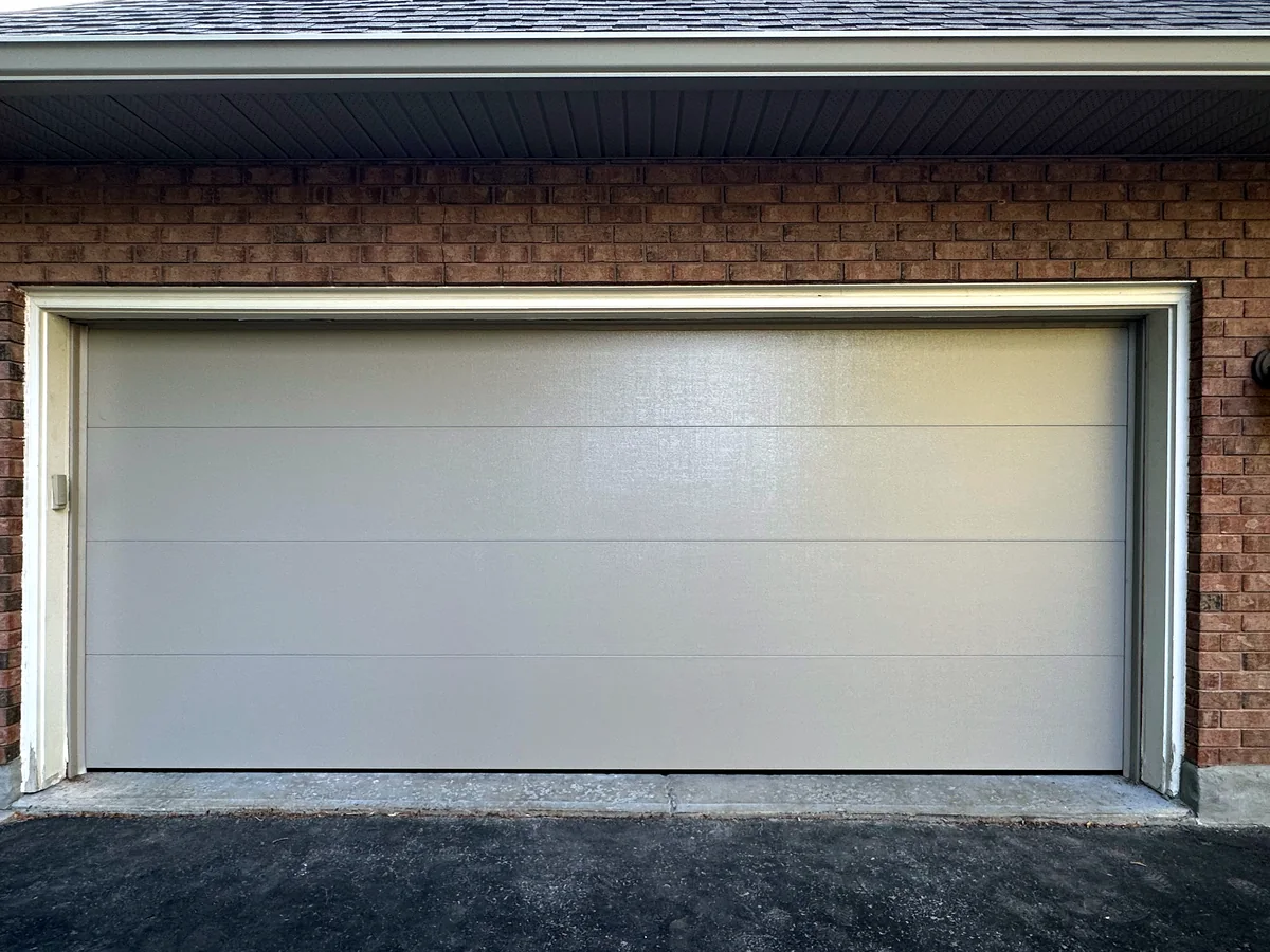 Wide white contemporary garage door at a brick home