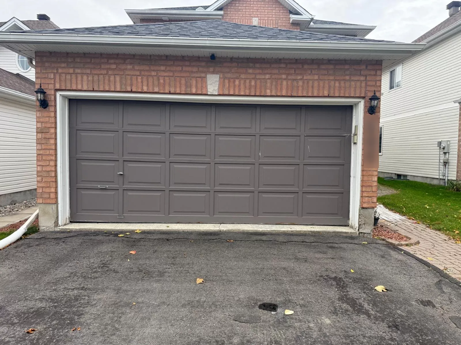 Dark taupe raised-panel double garage door on a Calgary brick garage before replacement