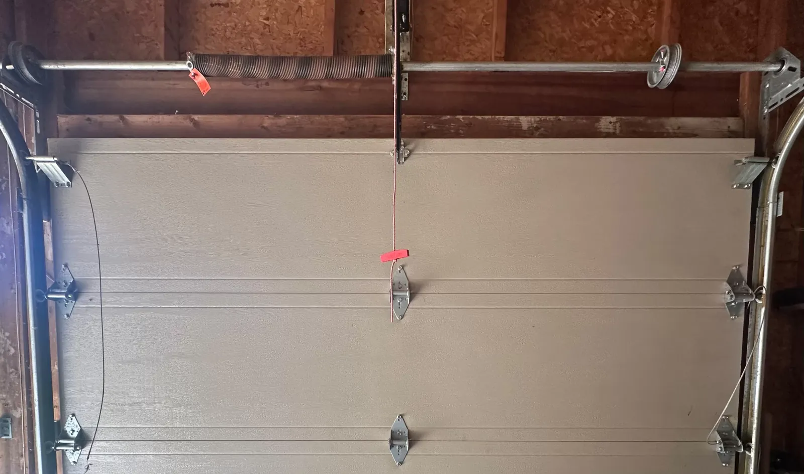 New torsion spring with a red tag installed above a Calgary garage door