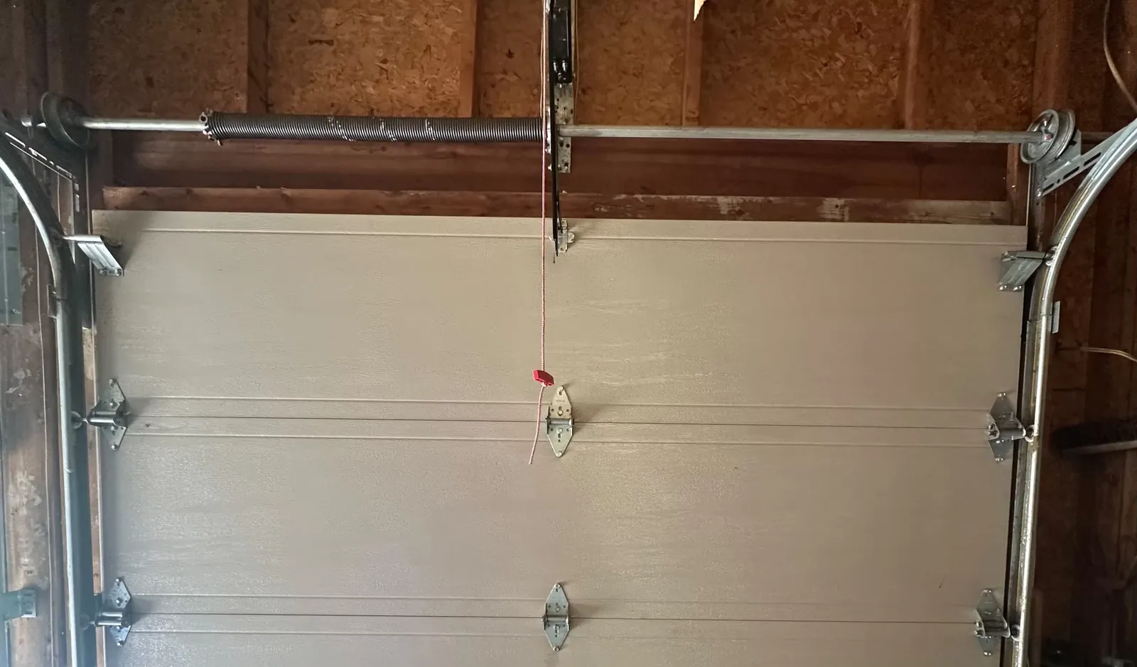 Old torsion spring on the shaft above a Calgary garage door before replacement