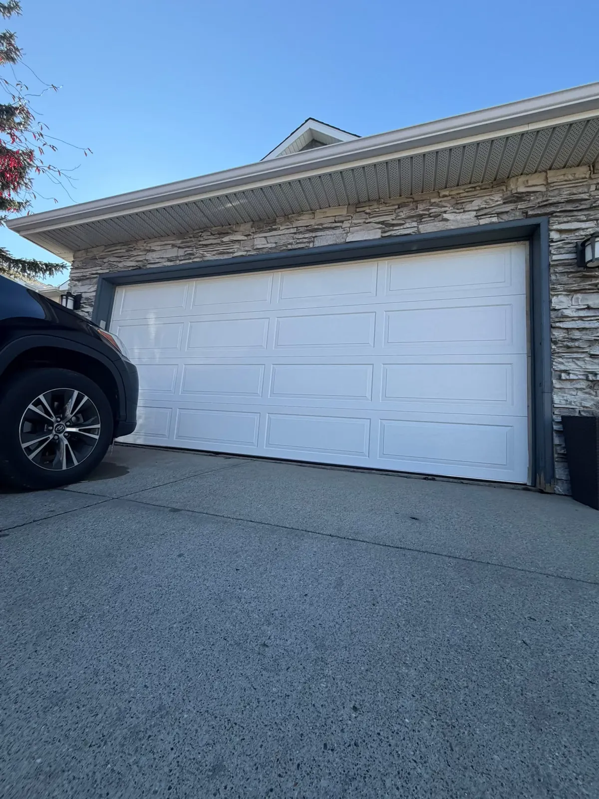 White Richards-Wilcox Raised Ranch R18 insulated garage door installed on a Calgary home with stone trim